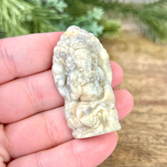 a hand holding a small piece of white marble