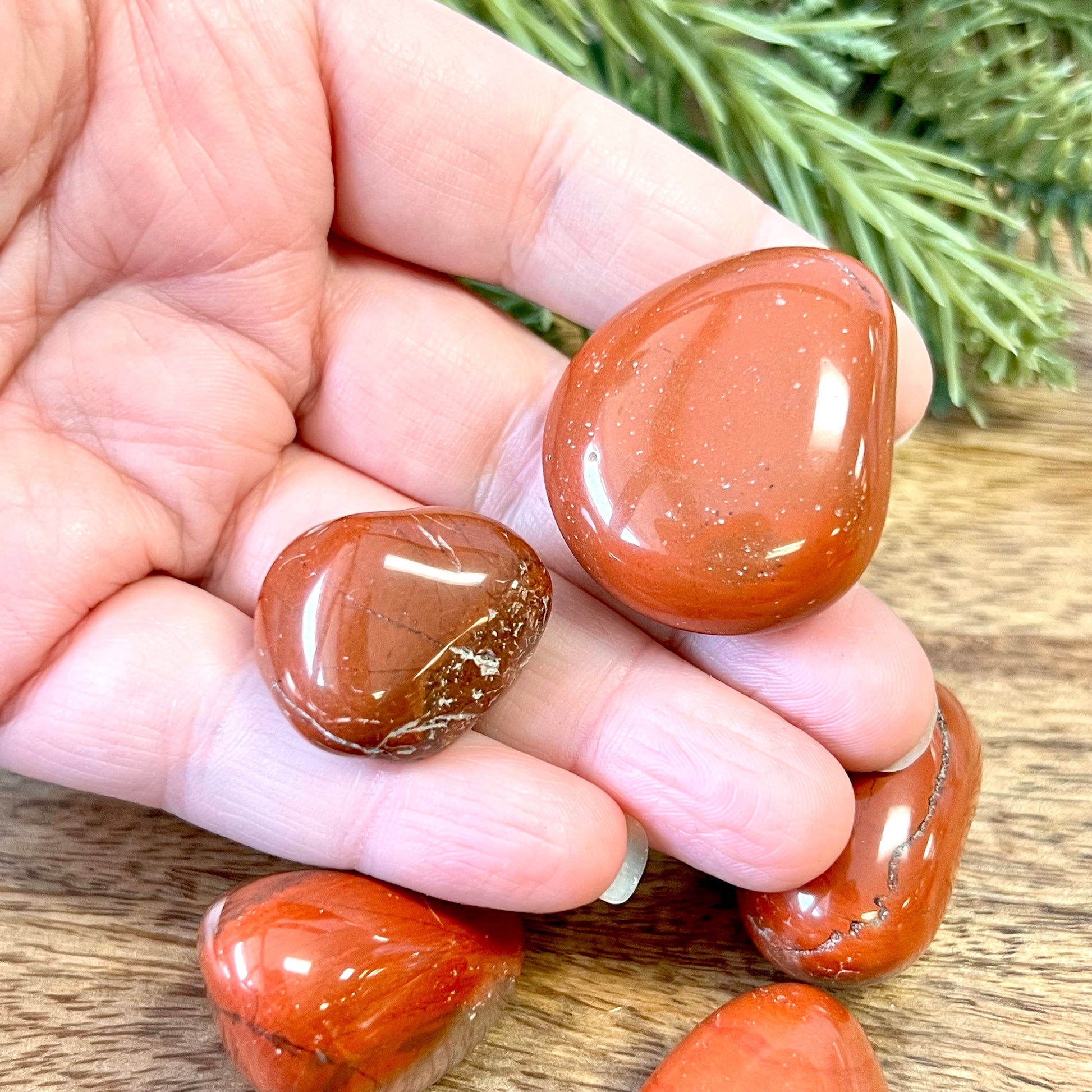 a group of large red Jasper tumbled crystals in a person's hand
