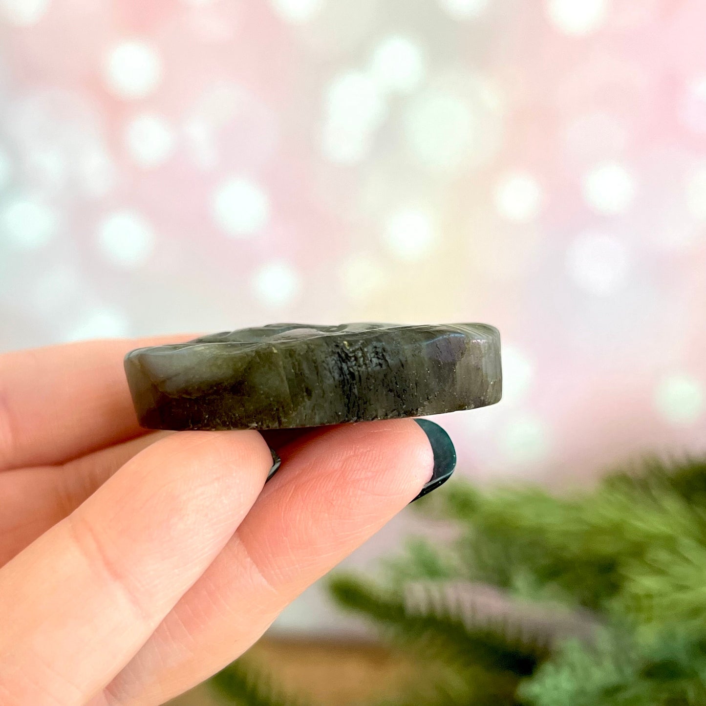 Image of a round carved stone cabochon made from Labradorite crystal. On the front is a lion's head, and the back is flat.