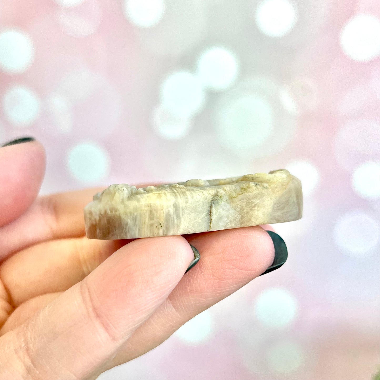 Image of a carved cabochon featuring a crouching tiger mid roar. The front is carved and the back is flat. It's made from Sunstone in Moonstone crystal.