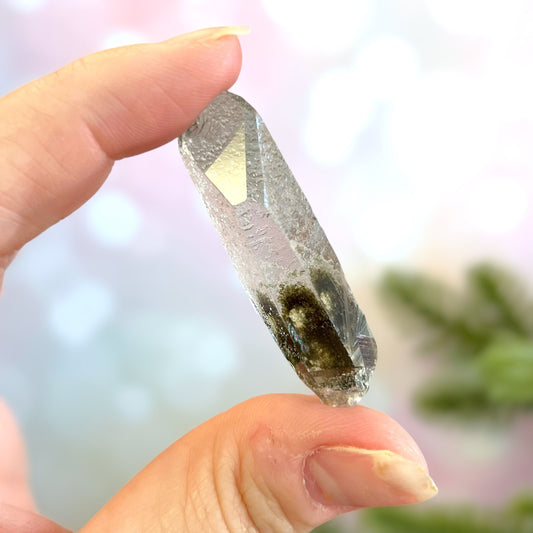 Close up of a small garden Quartz crystal point with chlorite inclusions. This mineral specimen is also called Lodolite, and is natural.
