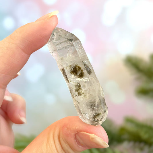 Close up of a small garden Quartz crystal point with chlorite inclusions. This mineral specimen is also called Lodolite, and is natural.