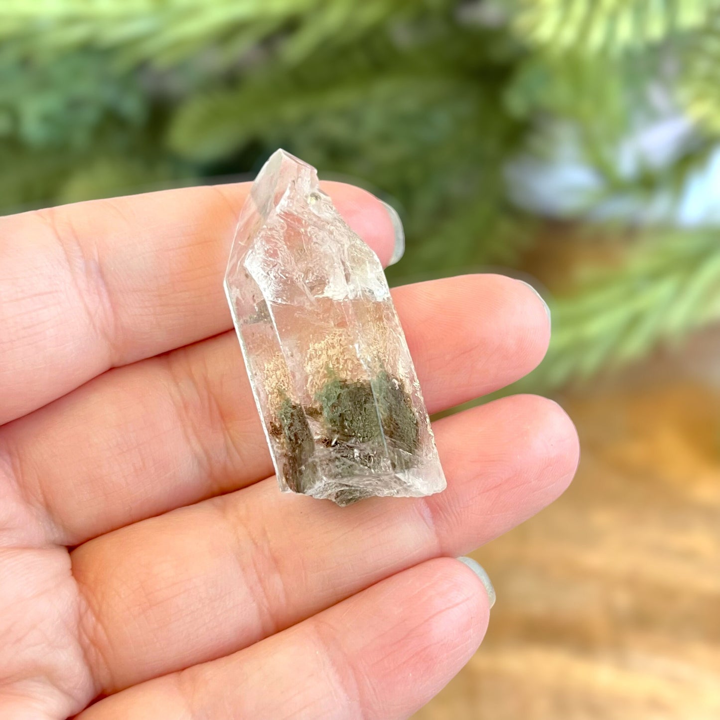 Close up of a small garden Quartz crystal point with chlorite inclusions. This mineral specimen is also called Lodolite, and is natural.