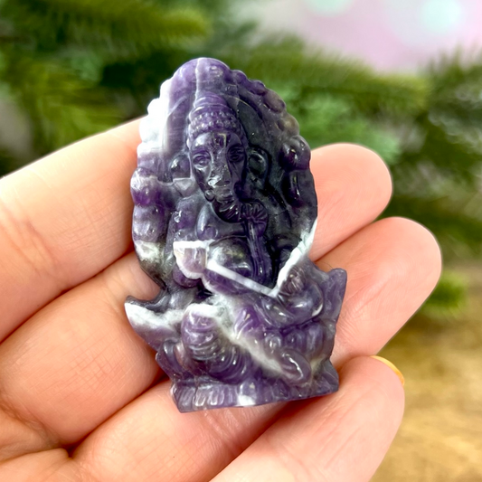 a hand holding a small purple and white statue