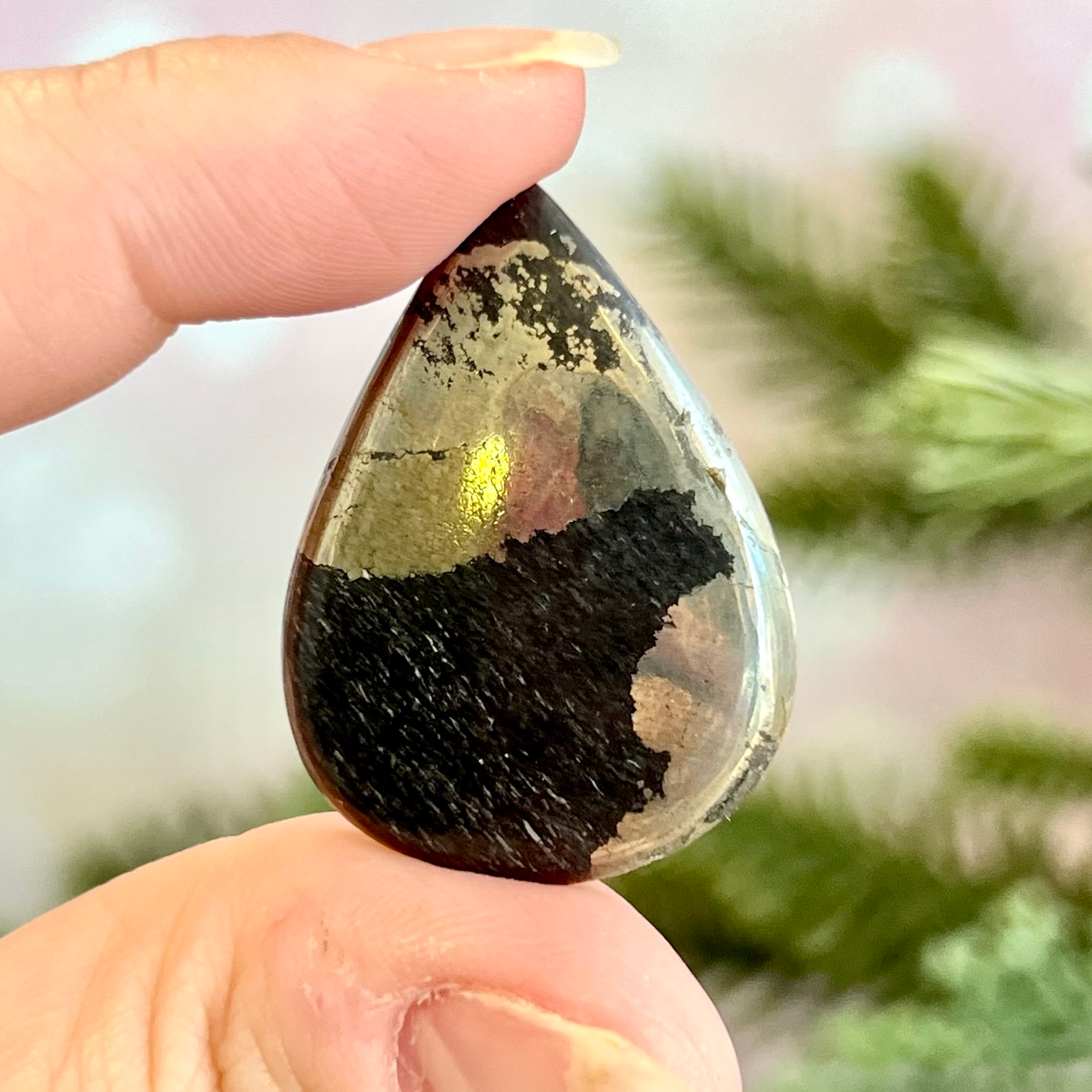 a person holding a black and gold tear shaped object