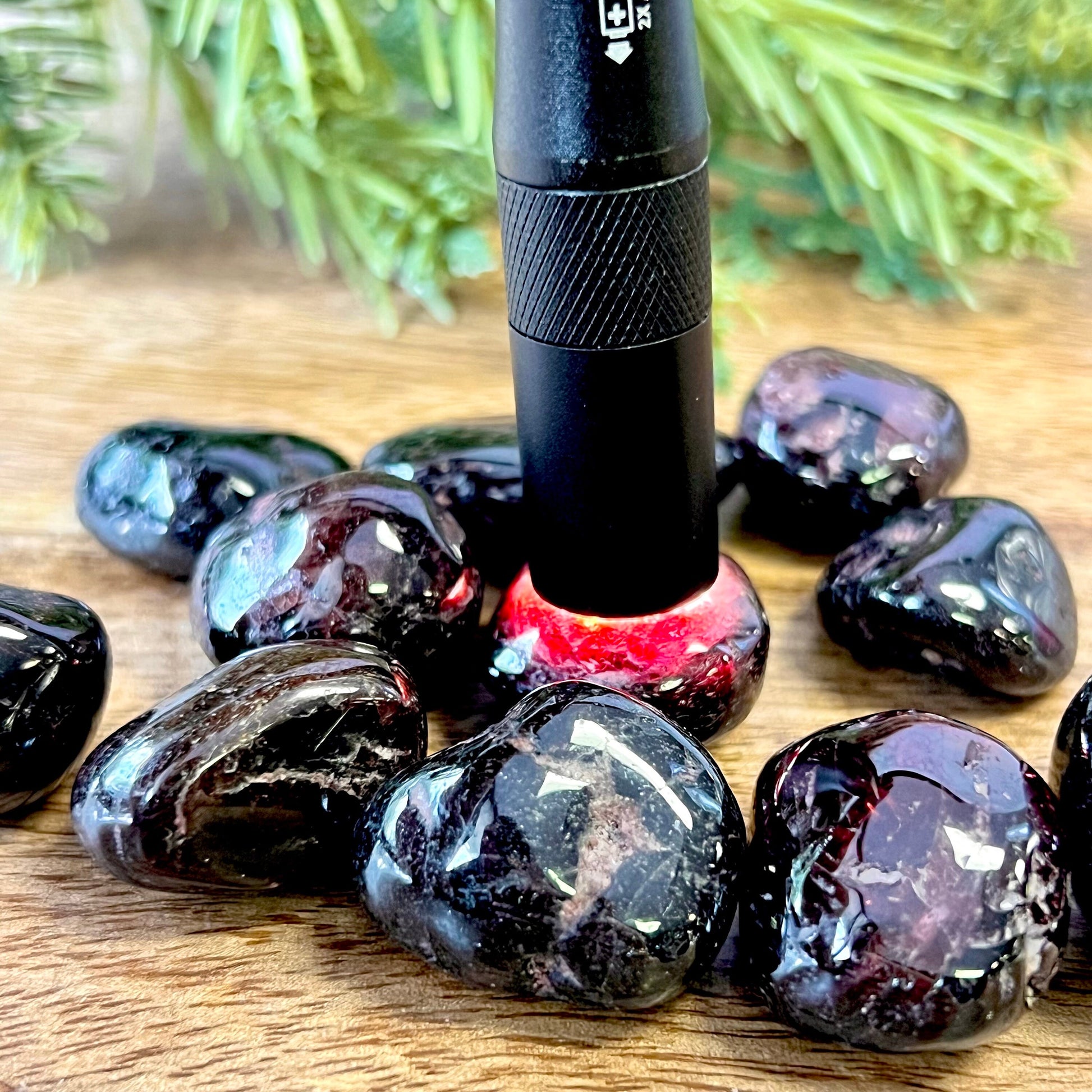 a flashlight illuminating a group of very dark red garnet tumbled crystals