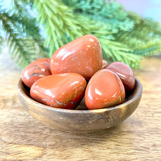 a group of large red Jasper tumbled crystals in a wooden bowl