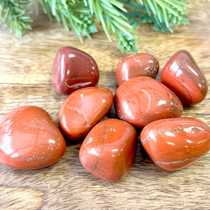 a group of large red Jasper tumbled crystals on a wooden background
