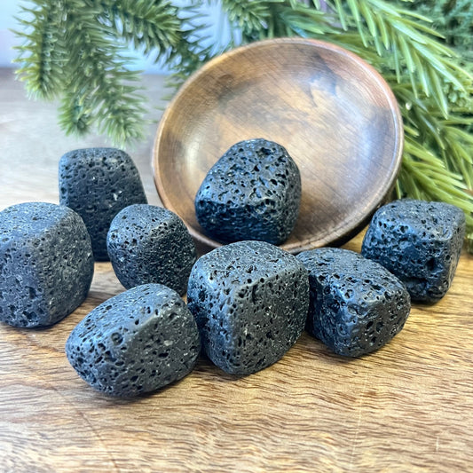 Group of semi-polished Lava Stone crystal tumbles in a wooden bowl. They are a satin matte texture with lots of natural holes