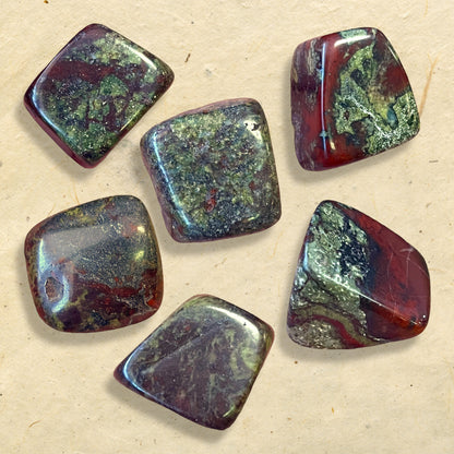 Group of green and red tumbled crystals. They are Dragon Blood Stone, and a polished cube shape.