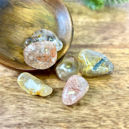 a group of Golden rutilated quartz tumbled crystals in a wooden bowl