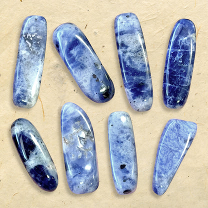 collage of a group of blue and white sodalite tumbled crystals. They are long oval dagger shapes