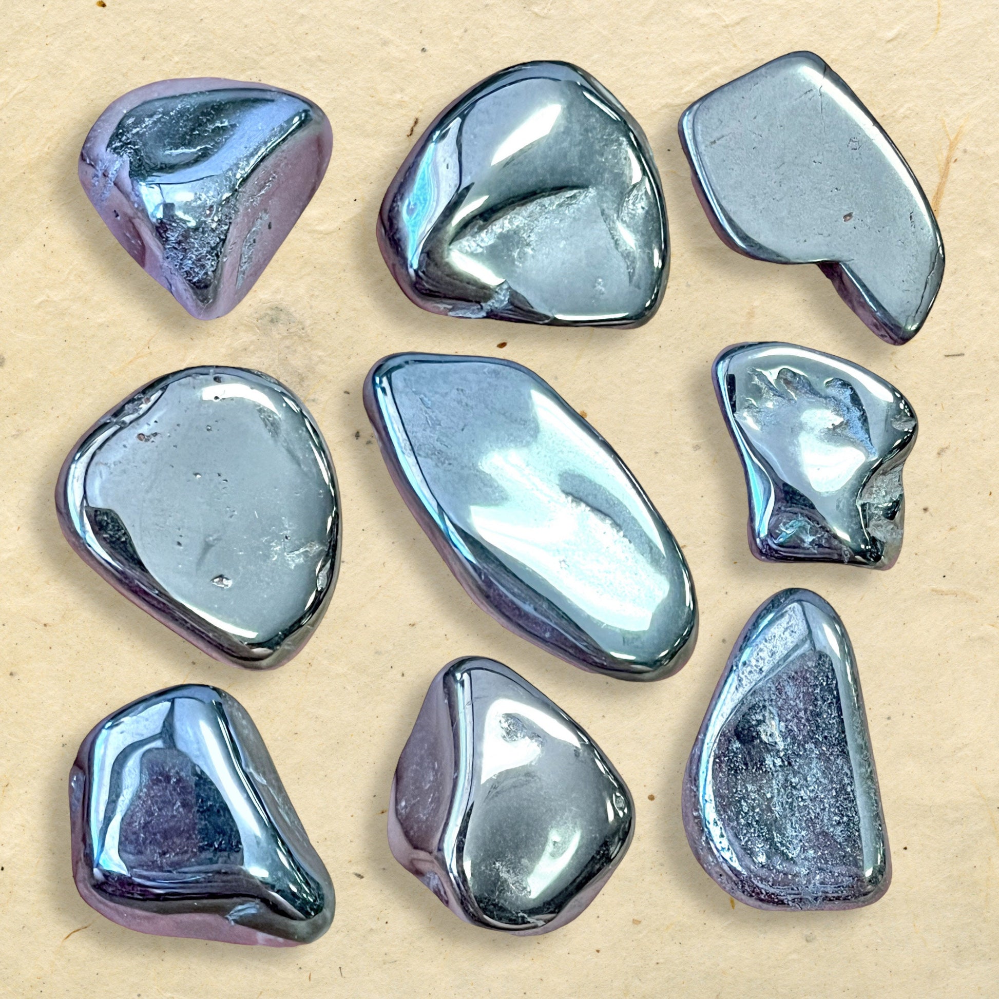 Collage of a Group of polished Hematite crystal tumbles. They are a metallic looking black color and smooth.