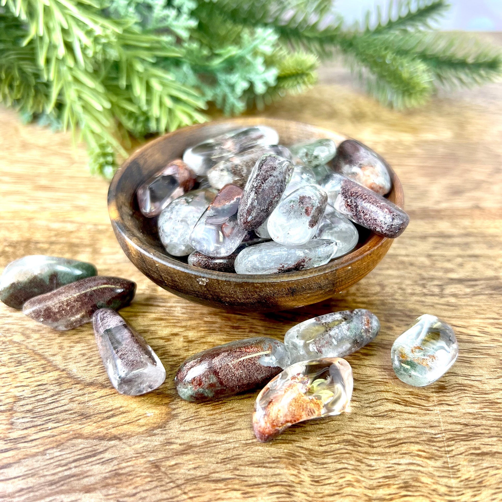 a wooden bowl filled with lodolite Garden Quartz tumbled crystals