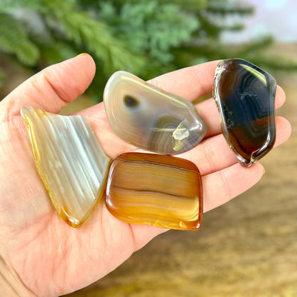 A person holding a bunch of polished agate slices in their hand. Agate crystals are natural and not dyed.