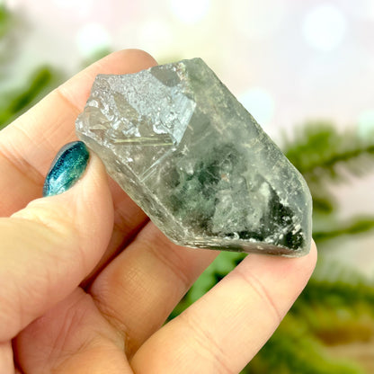 Close up of a small garden Quartz crystal point with chlorite inclusions. This mineral specimen is also called Lodolite, and is natural.