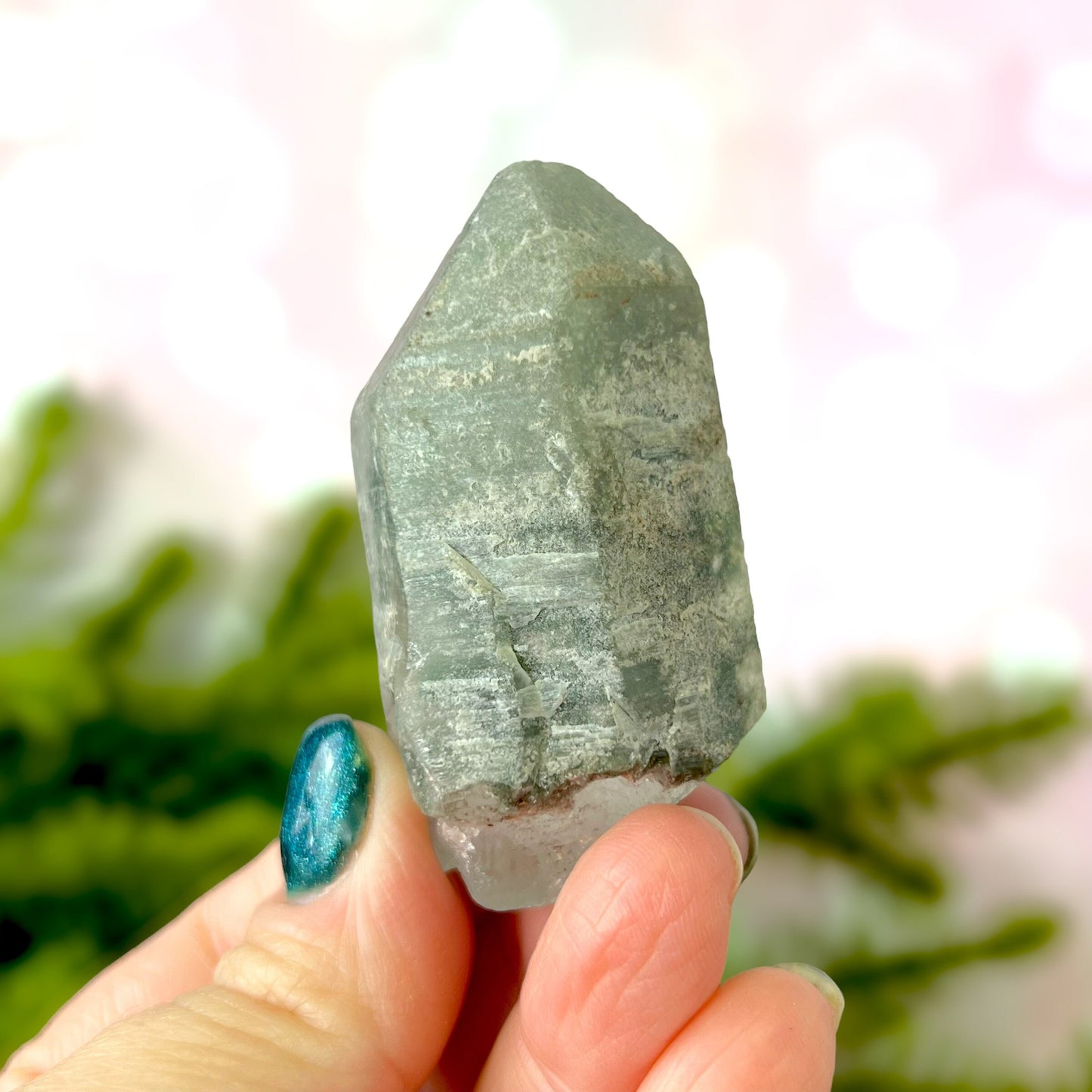 Close up of a small garden Quartz crystal point with chlorite inclusions. This mineral specimen is also called Lodolite, and is natural.