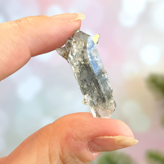 Close up of a small garden Quartz crystal point with chlorite inclusions. This mineral specimen is also called Lodolite, and is natural.